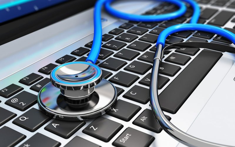 Healthcare and medicine or computer antivirus protection and repair maintenance service concept: macro view of blue stethoscope on business office laptop notebook keyboard with selective focus effect